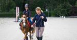 Adult instructor with child on pony in arena. From Little Trainers, Big Trainers Grow. Teaching kids to train their ponies.